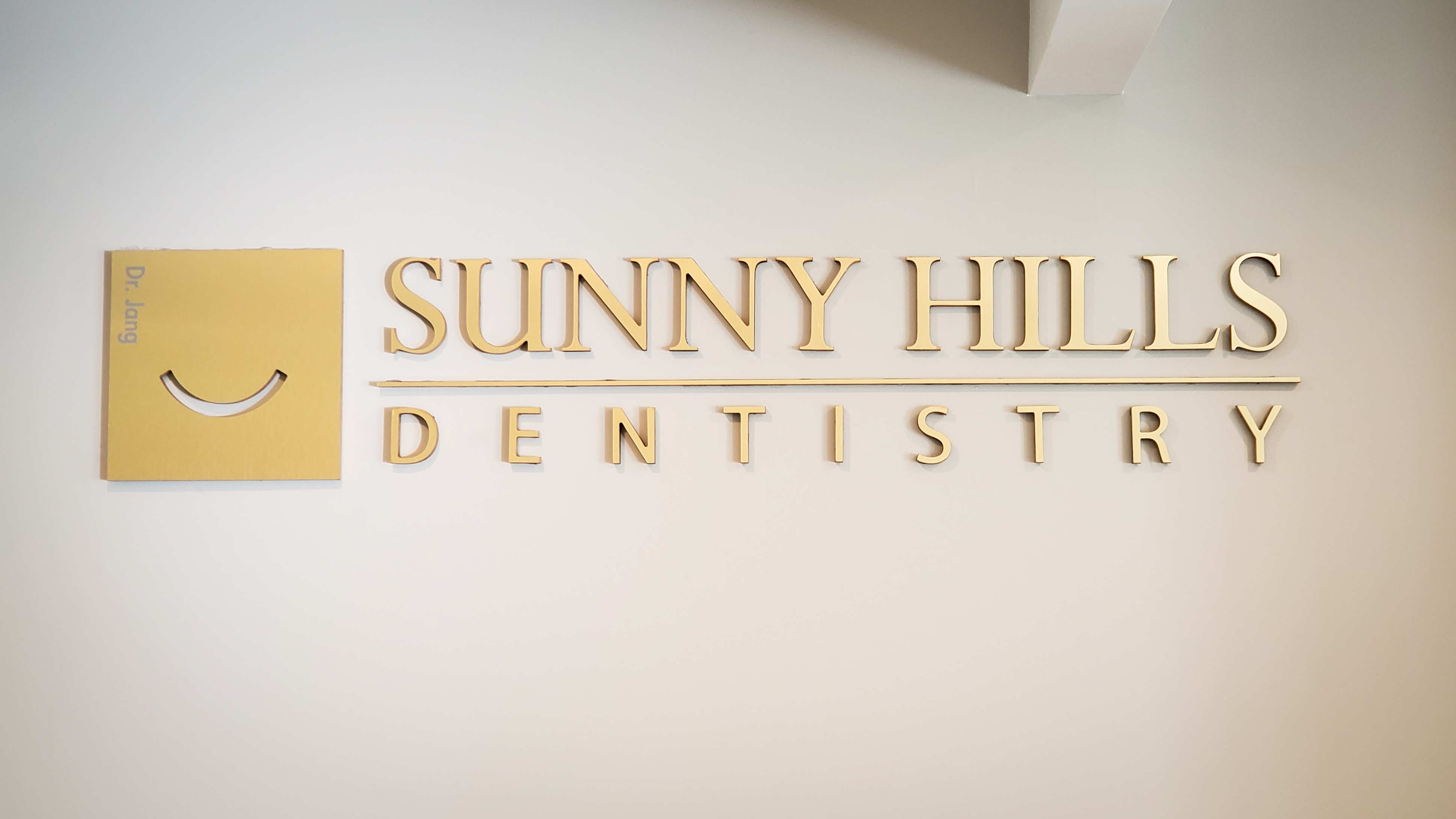 Sunny Hills Dentistry gold wall sign — Dr. Jang's office